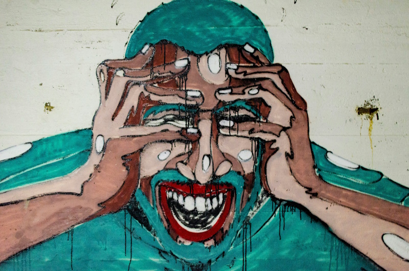 A mural of a man holding his head in both hands expressing pain.