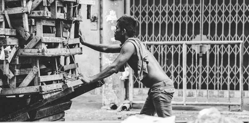 Hard working man pushing a wagon full of pallets.