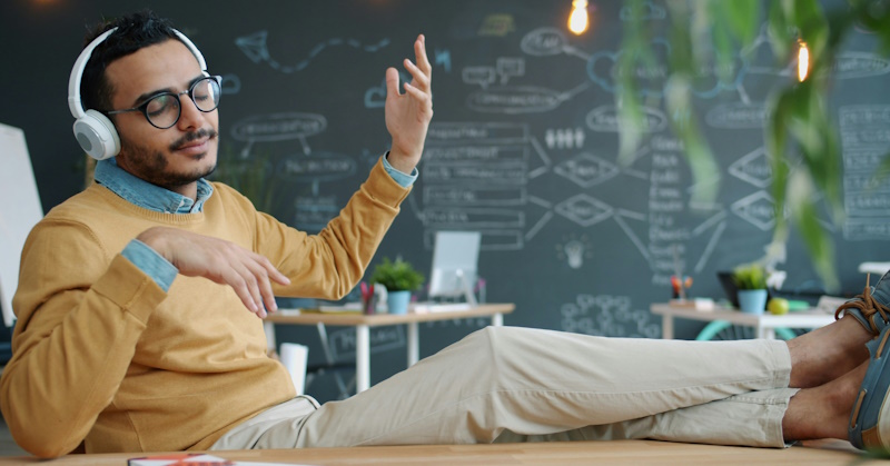 Man enjoying music with his feet on a desk with headphones on.