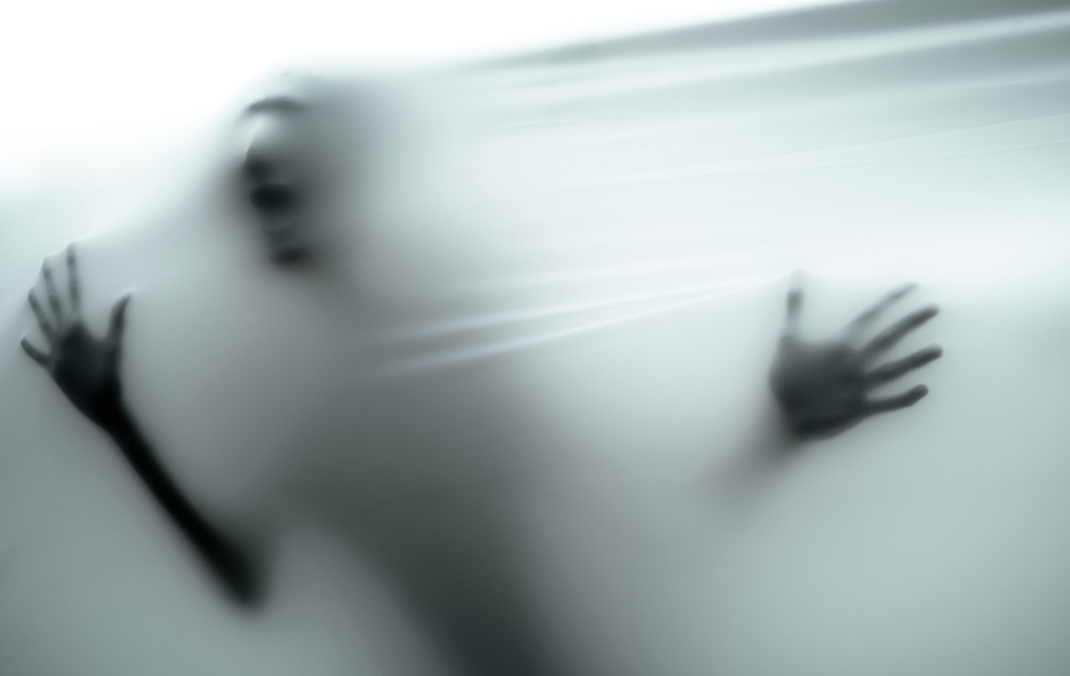 A terrified blurry figure trying to breakthrough a partly translucent barrier.